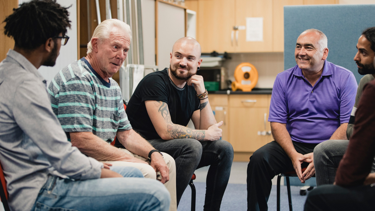 A group of men sitting in a circle in a meeting room.