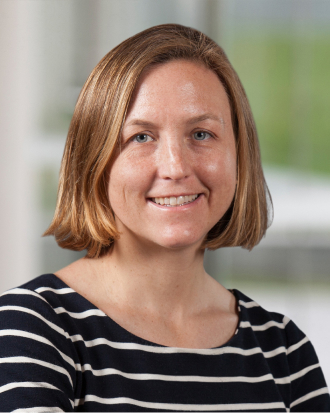 Kimberly J Reidy, MD, FAAP, seen wearing a blue and white horizontal striped shirt. She smiles toward the camera.