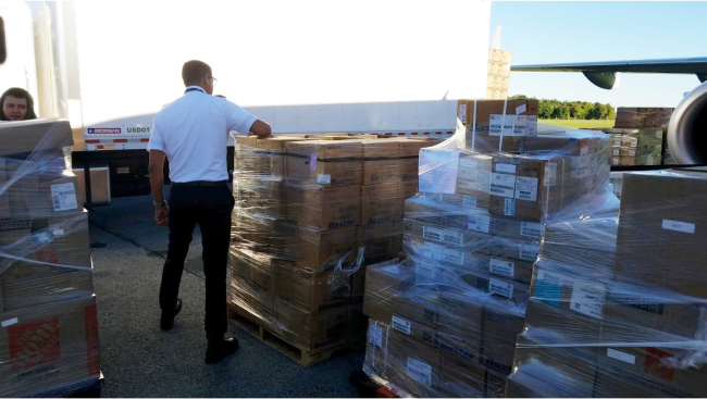 A crew member breaks down one of several pallets for loading into the plane.