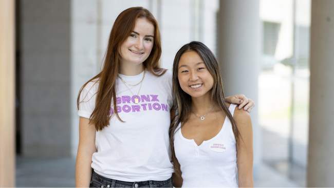 Two students smile toward the camera. 