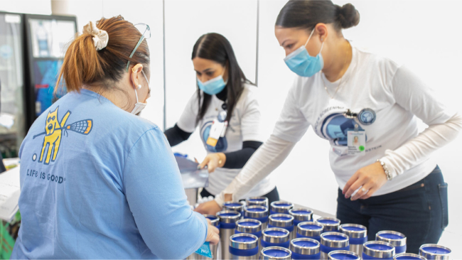 Volunteers stock a screening fair table with cups to give away.