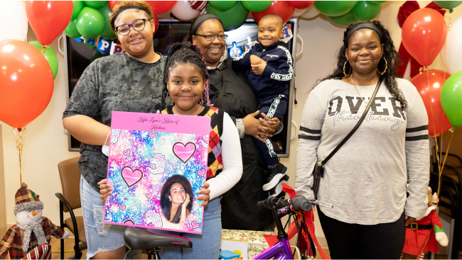 Smiling families with gifts from the Kisses for Kyla program