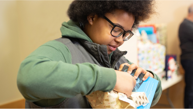 A child works to unwrap a package.