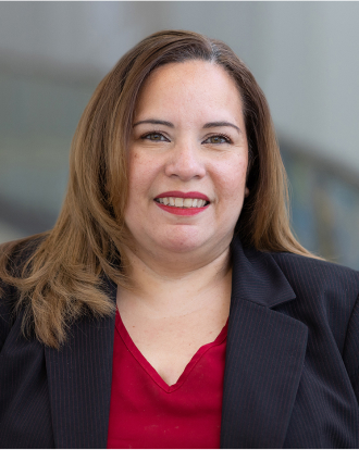 Denise Galeano dresses in a black blazer and burgundy top.