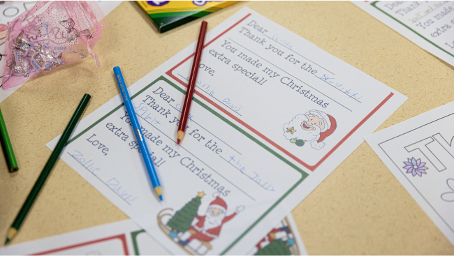 Present tags and colored pencils lie on a table.