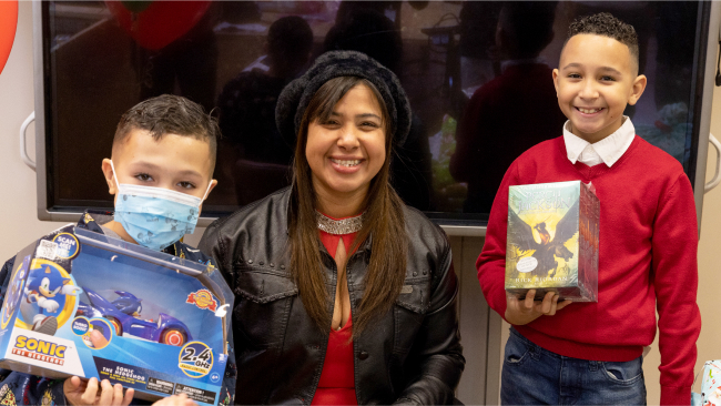 Children smile at the camera having received gifts from Kisses for Kyla.