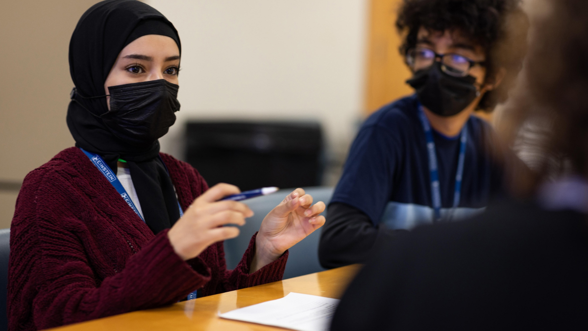 A diverse group of students sit around a table talking.