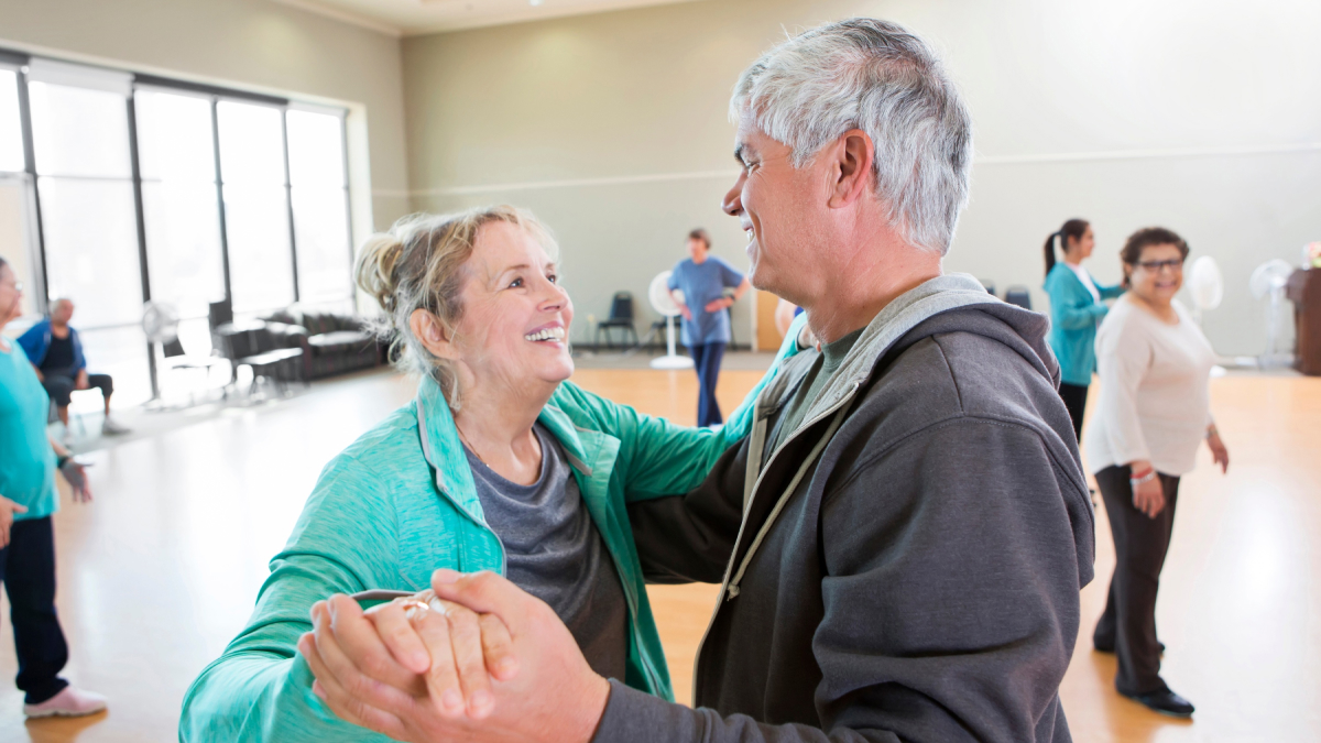 Two people dance in an informal dance class setting. 