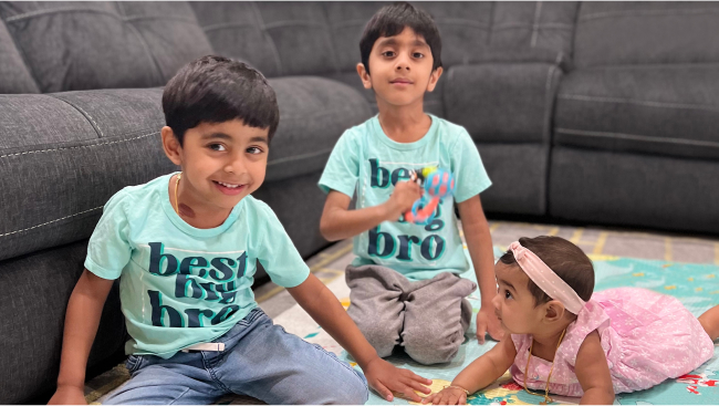 Baby Elsa in pink and her siblings in matching mint green t-shirts.