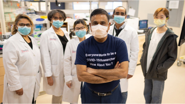 Scientists in masks stand for a group photo.