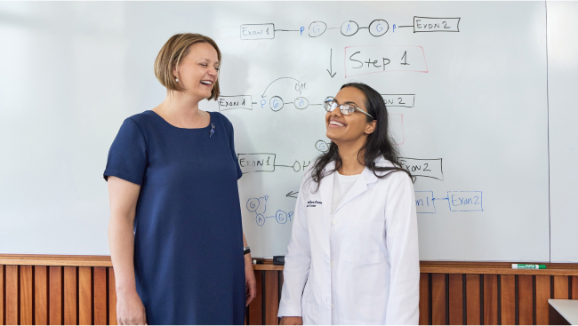 Two scientists present in front of a white board.