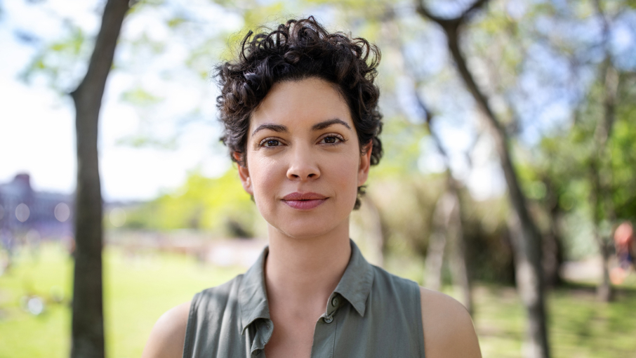 A young woman in a summer shirt looks toward the camera.