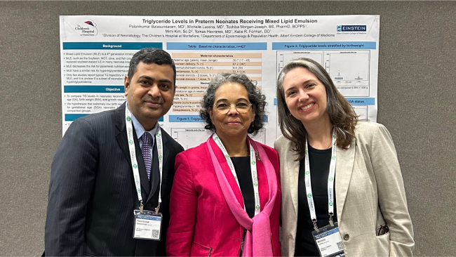 Three attendees stand in front of a scientific presentation poster.