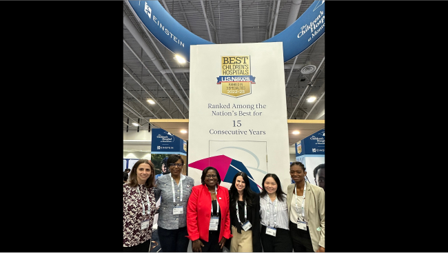 A group of attendees stand in front of a large award banner.