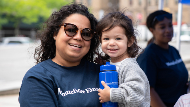 A smiling child and happy grownup smile for a picture at Bronx Week 2023.