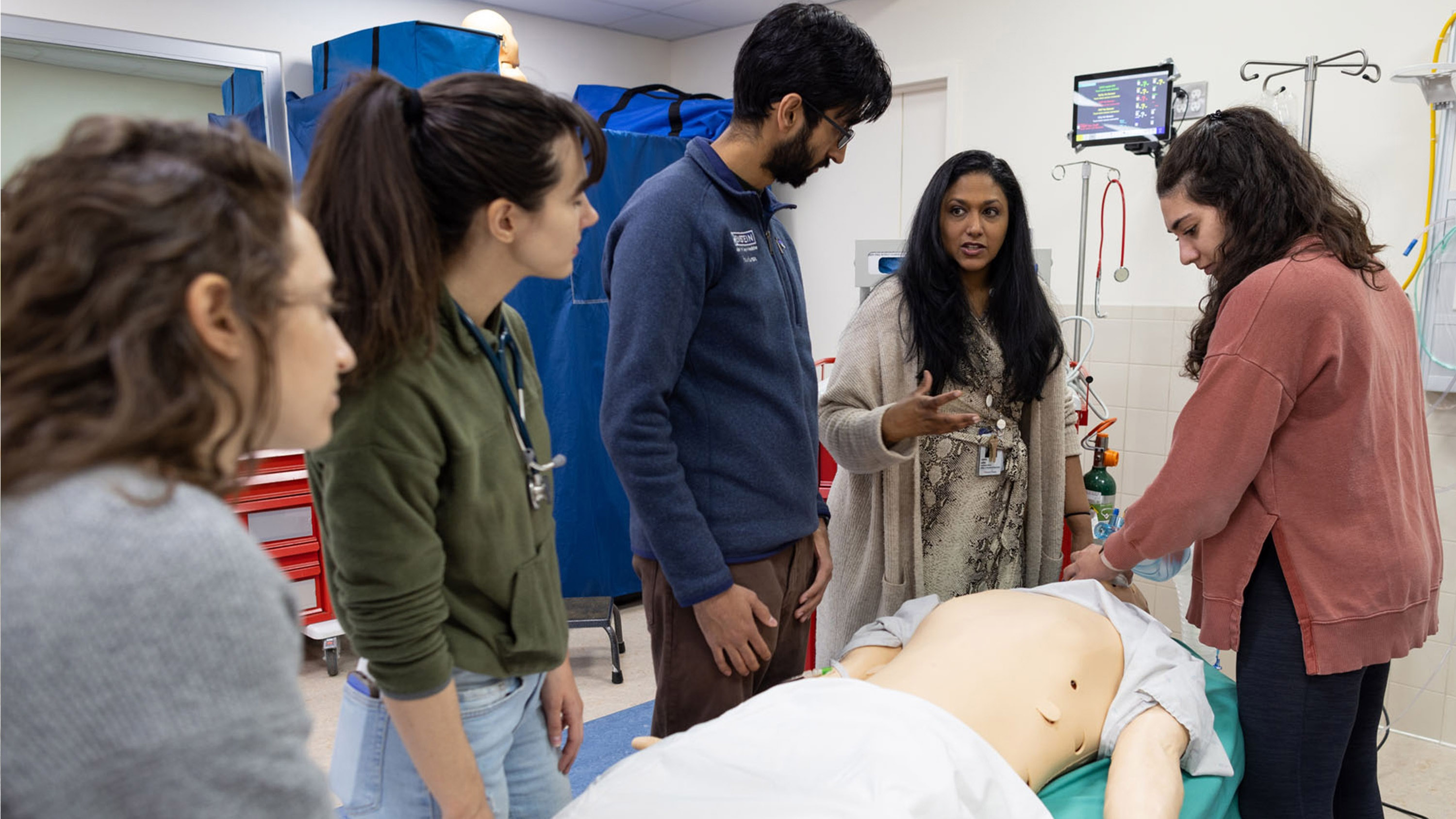 Residents gather around a model to practice a procedure.