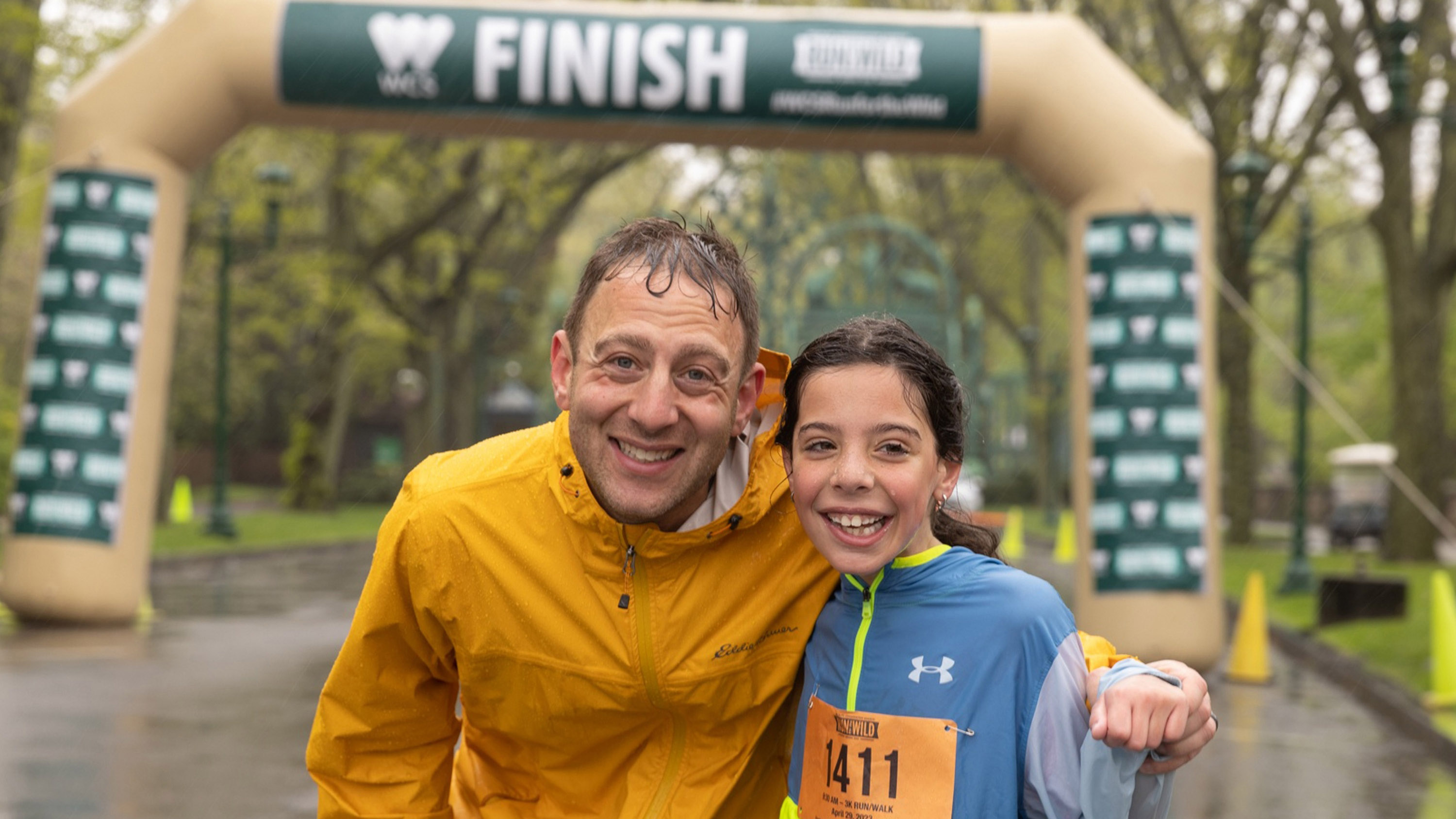 Rain soaked runners smile for the camera at the finish line.