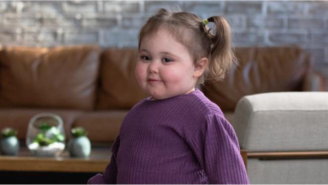 A cute child in pigtails smiles toward the camera.