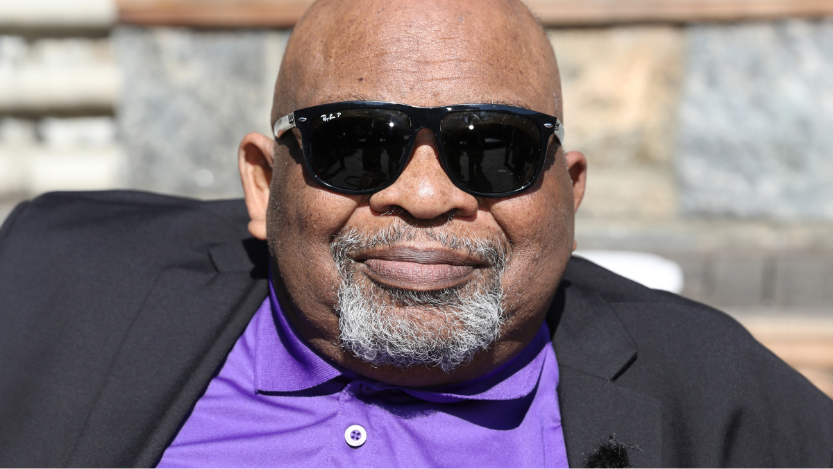 Dr. George K. Gresham, in a purple buttondown shirt and black suit jacket.