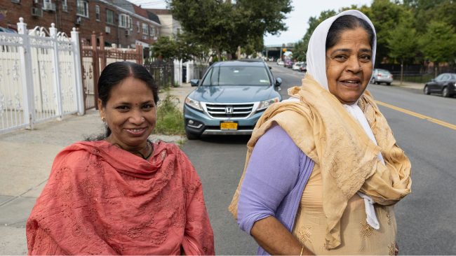 Two smiling women cross a street together.