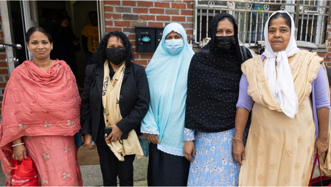 A group of women stand in front of a brick building.