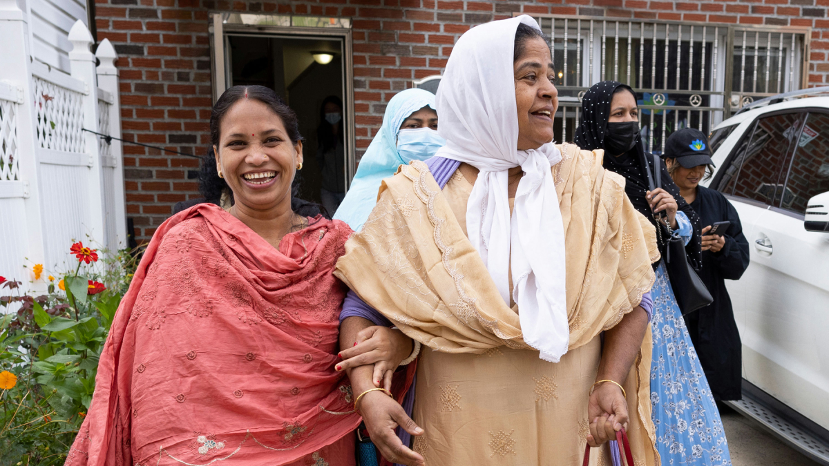 Two smiling patients leave a brick building.