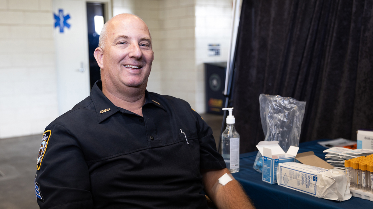 A smiling participant sits next to a testing station at the event.