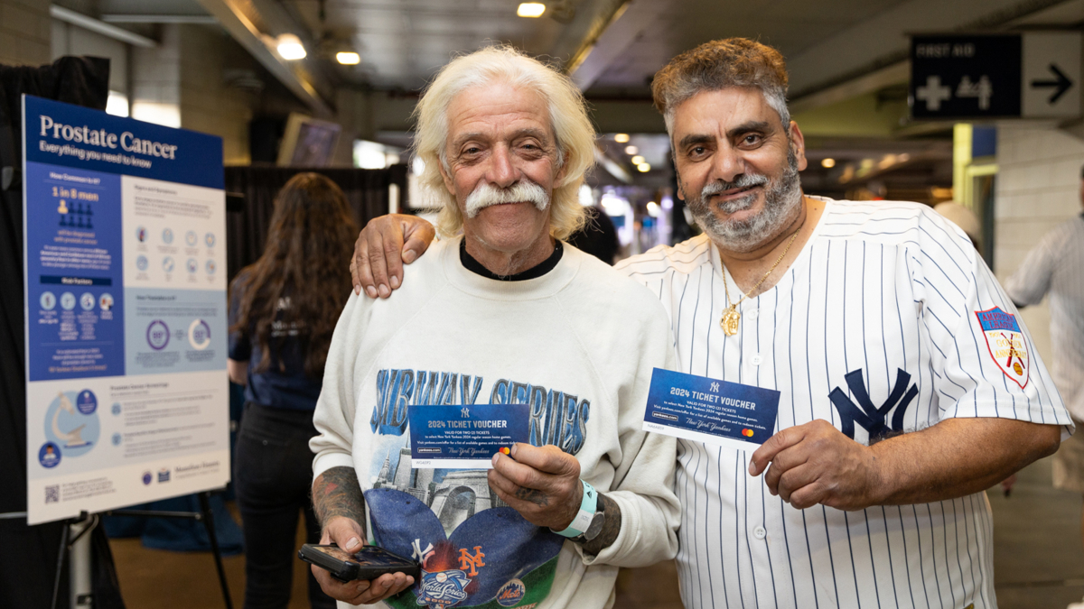 Smiling participants in Yankees gear hold up materials from the event.