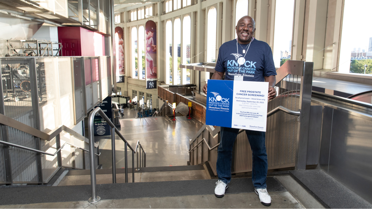 A smiling staff member holds up a sign to the event.