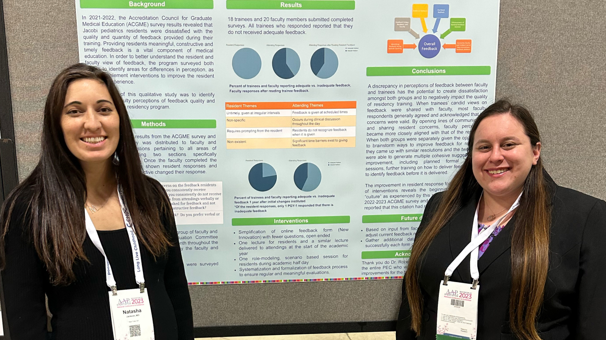 Two smiling attendees stand in front of a scientific poster.