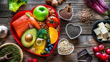 A heart shaped red dish holds a variety of heart and kidney healthy foods.