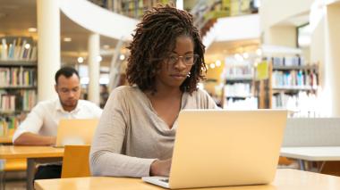 Students work on laptops in a library.