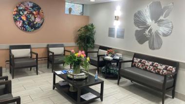 A refreshed, beautiful discharge lounge room featuring floral padded benches, wall art, and a green plant.