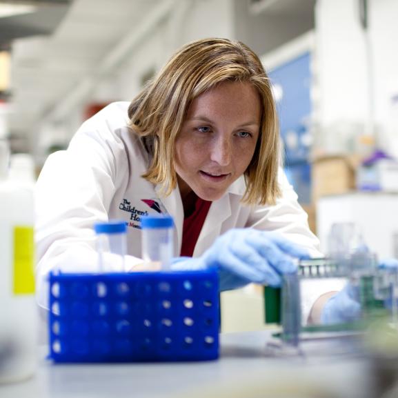 A researcher works on a lab bench running tests. 